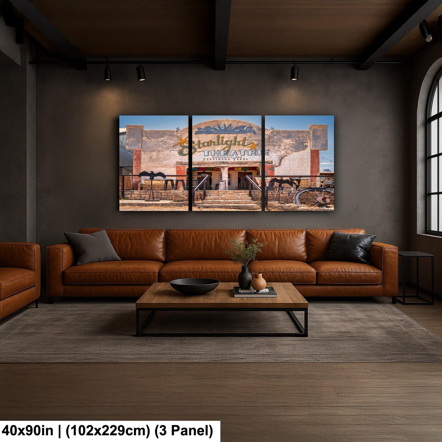 The image is a modern living room with a large, three-panel artwork depicting a building with a sign that reads "Starlight". The artwork is mounted on the wall above a brown leather sofa and a wooden coffee table.
