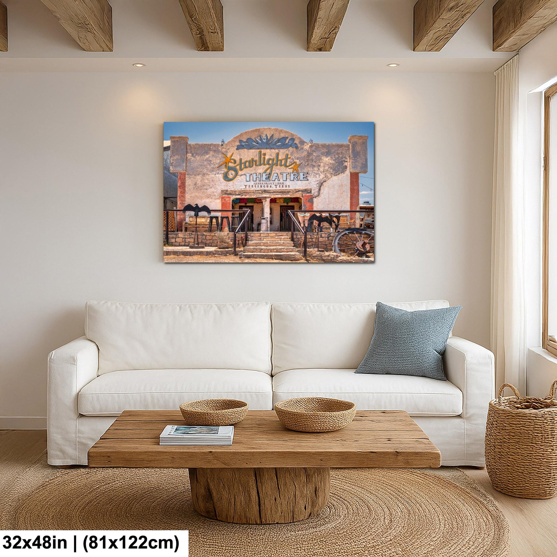 a living room with a white sofa, a wooden coffee table, and a framed picture of a theater called Starlight Theatre hanging on the wall.