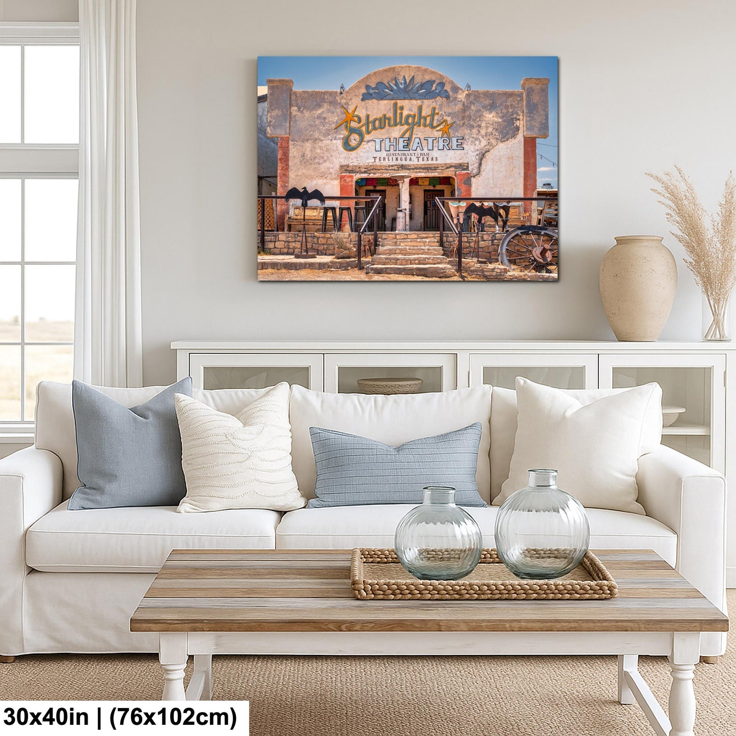 a living room with a white sofa, a wooden coffee table, and a framed picture of a theater above it.