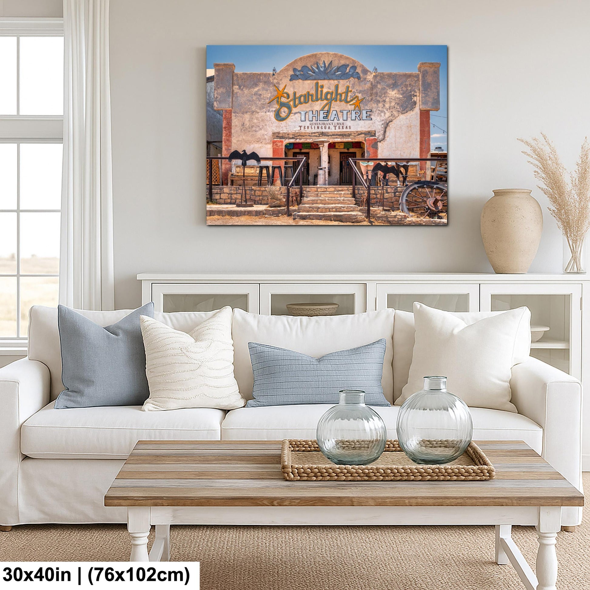 a living room with a white sofa, a wooden coffee table, and a framed picture of a theater above it.
