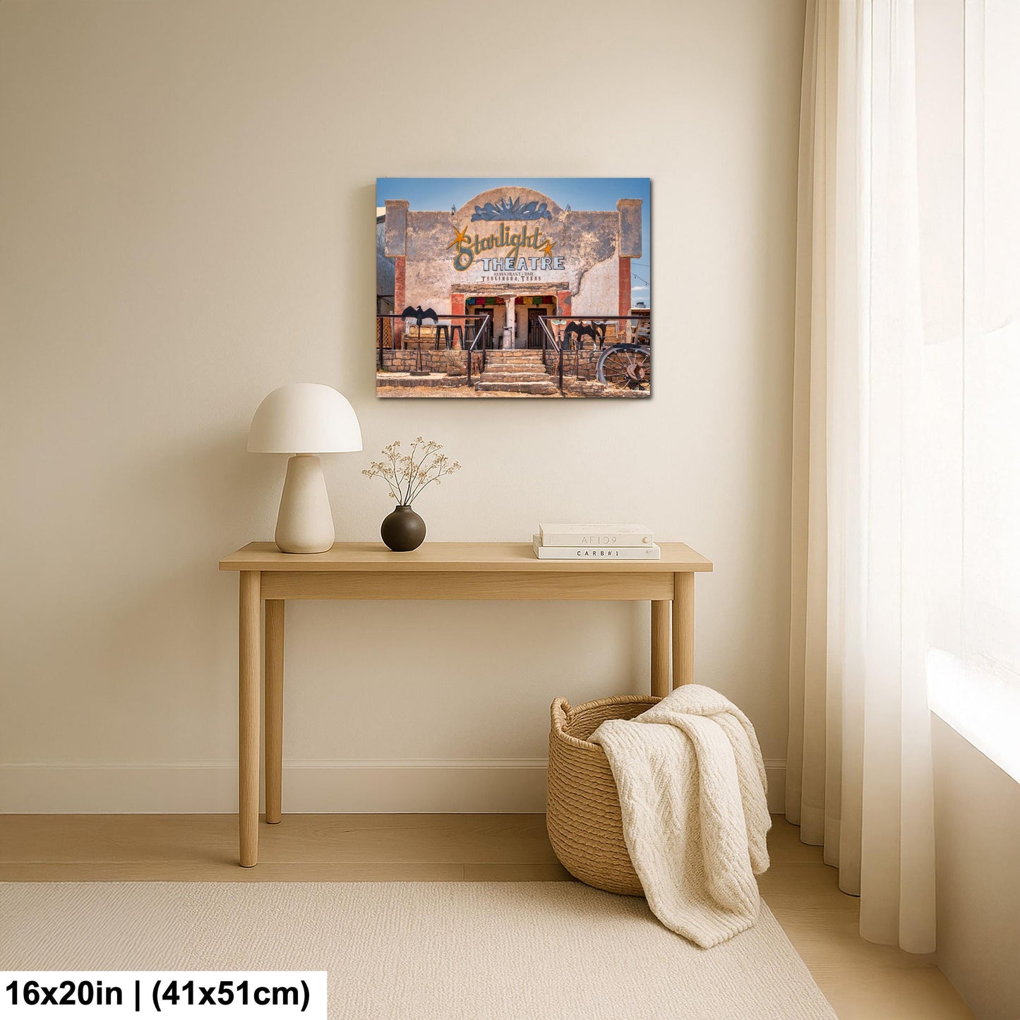 a cozy living room with a wooden table, a lamp, a basket, and a framed picture of a building.
