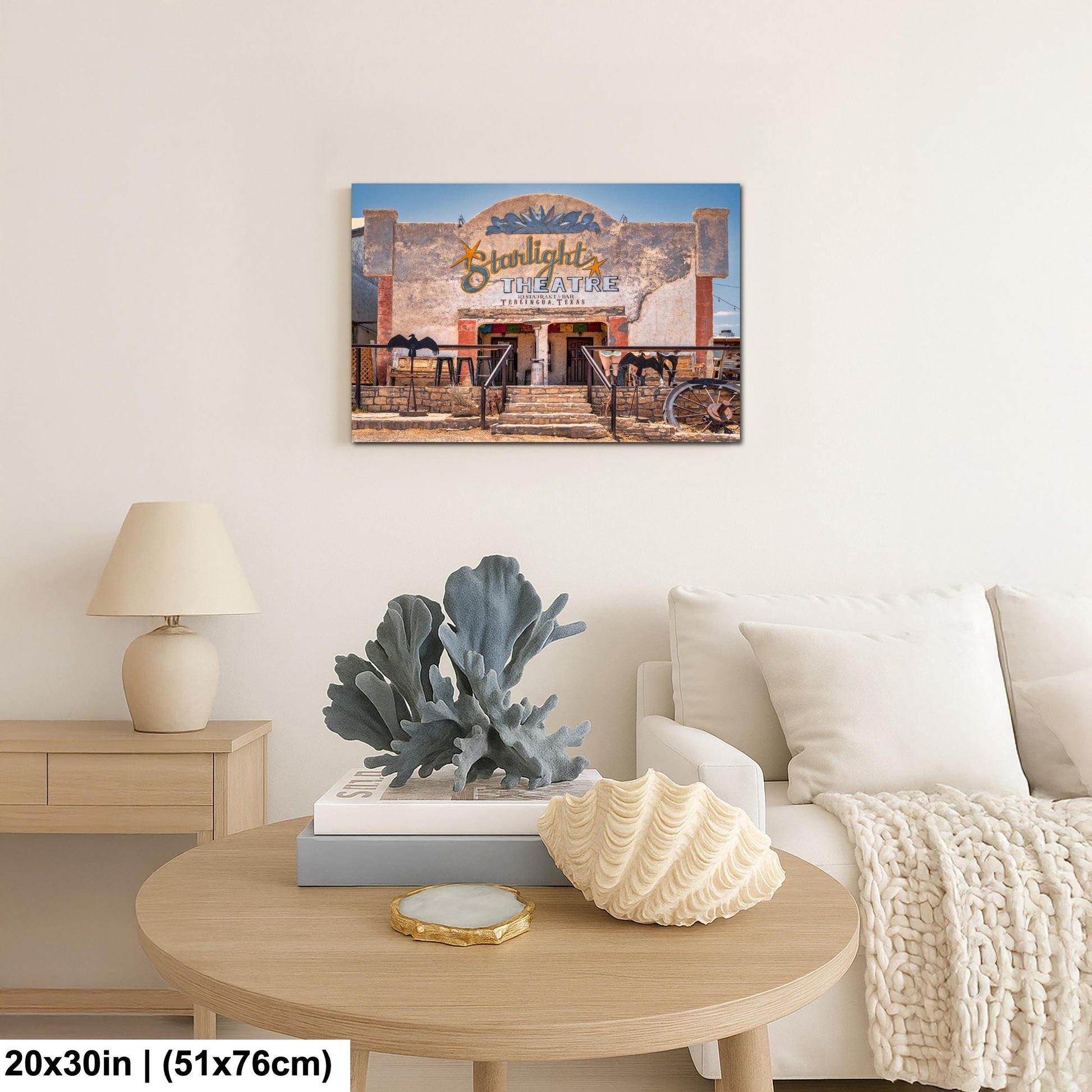 a living room with a wooden coffee table, a lamp, a couch, and a framed picture of a building.